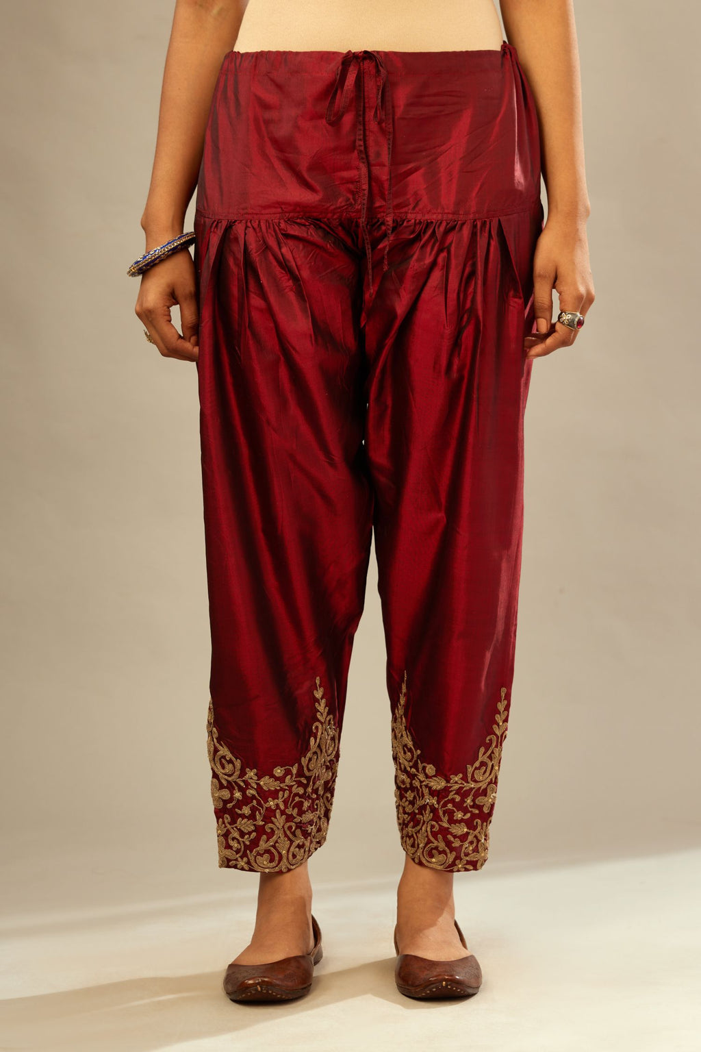 Maroon silk narrow salwar with light gold dori embroidery at hem.