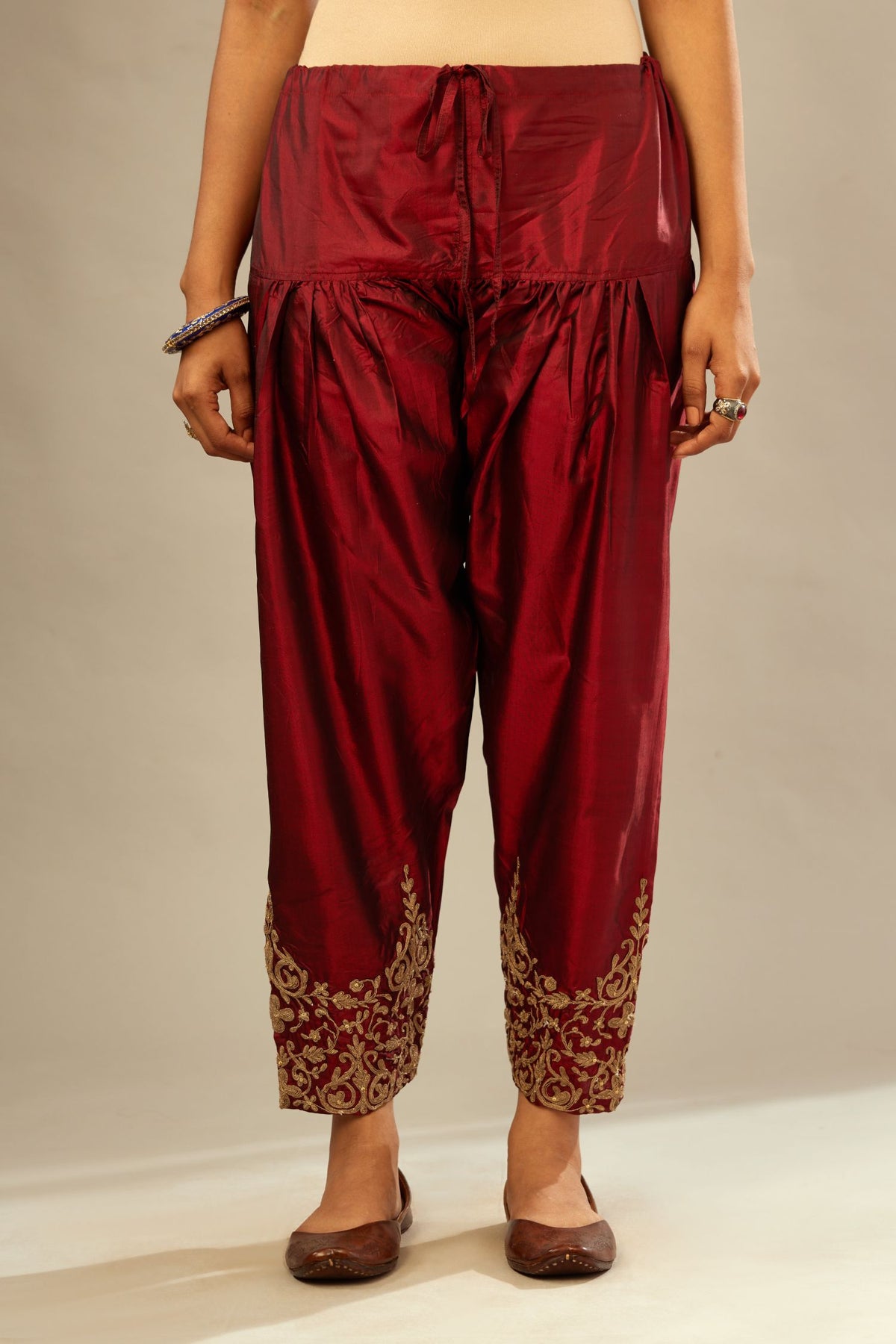 Maroon silk narrow salwar with light gold dori embroidery at hem.