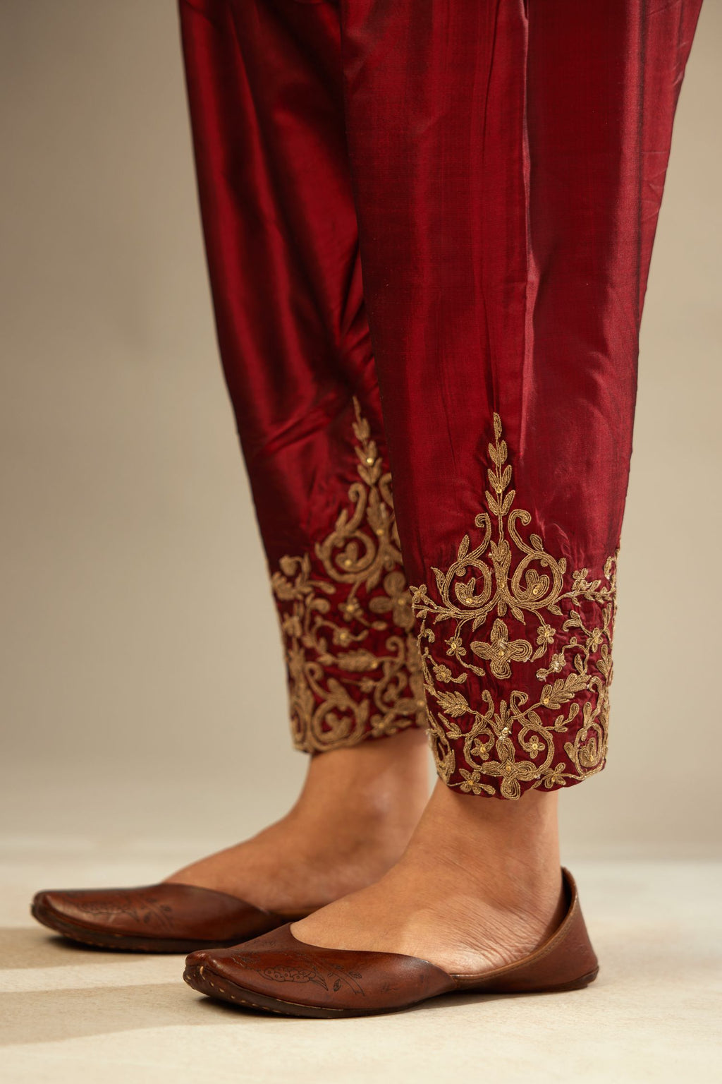 Maroon silk narrow salwar with light gold dori embroidery at hem.