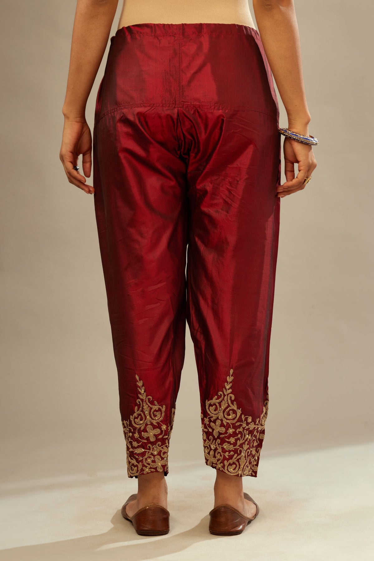 Maroon silk narrow salwar with light gold dori embroidery at hem.