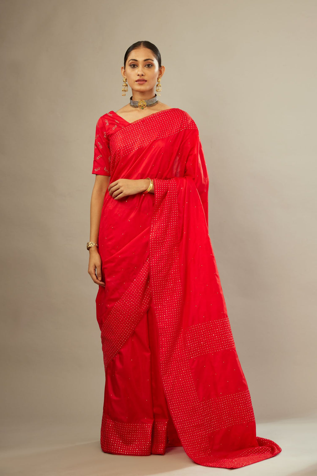 Red silk saree set with a broad border of hand embroidered geometrically aligned sequins and three horizontal bands at the pallu.