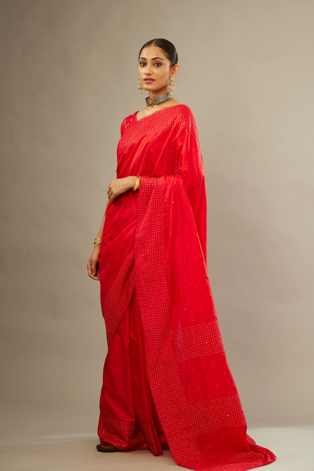 Red silk saree set with a broad border of hand embroidered geometrically aligned sequins and three horizontal bands at the pallu.