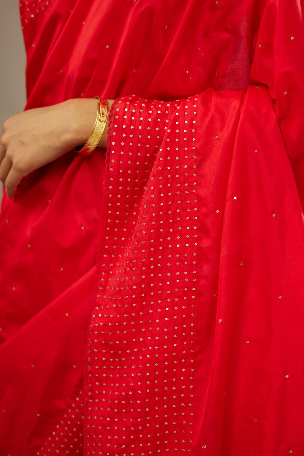 Red silk saree set with a broad border of hand embroidered geometrically aligned sequins and three horizontal bands at the pallu.