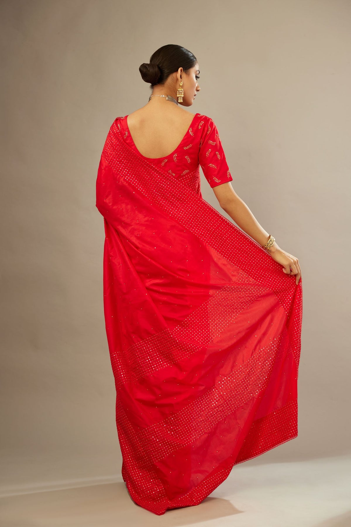Red silk saree set with a broad border of hand embroidered geometrically aligned sequins and three horizontal bands at the pallu.