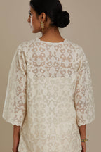 Off white cotton chanderi short top with all-over appliqué, highlighted with sequin, paired with off white cotton straight pants with appliqué detail at hem, highlighted with sequins.