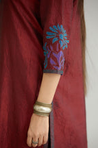 Maroon hand crushed silk kurta set with contrast silk fabric applique work at hem, side slits and sleeves with an embroidered neckline.
