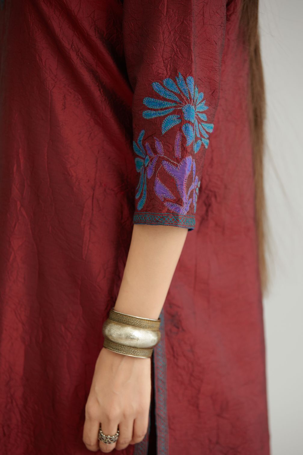 Maroon hand crushed silk kurta set with contrast silk fabric applique work at hem, side slits and sleeves with an embroidered neckline.
