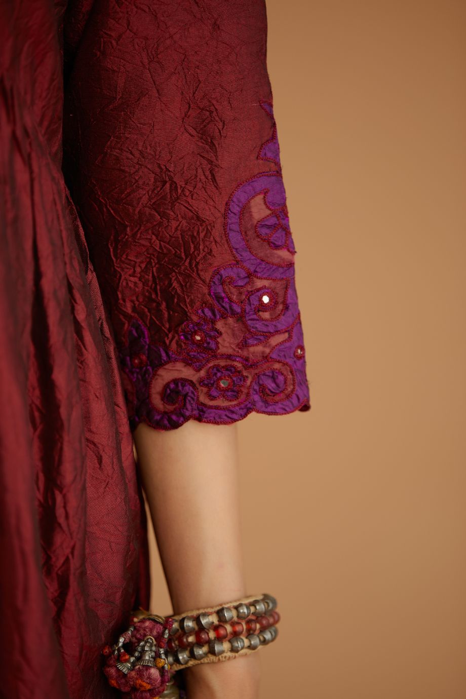 Maroon hand crushed silk kurta set with wavy empire waistline and gathers, with silk and organza cutwork embroidery, highlighted with hand attached mirrors.