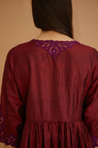 Maroon hand crushed silk kurta set with wavy empire waistline and gathers, with silk and organza cutwork embroidery, highlighted with hand attached mirrors.
