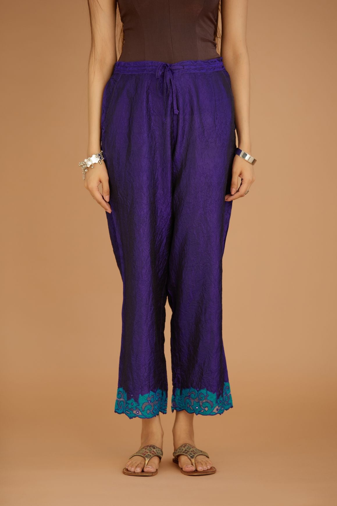 Blue hand crushed silk pants with contrast silk and organza fabric cutwork embroidery at bottom hem, highlighted with hand attached mirrors.
