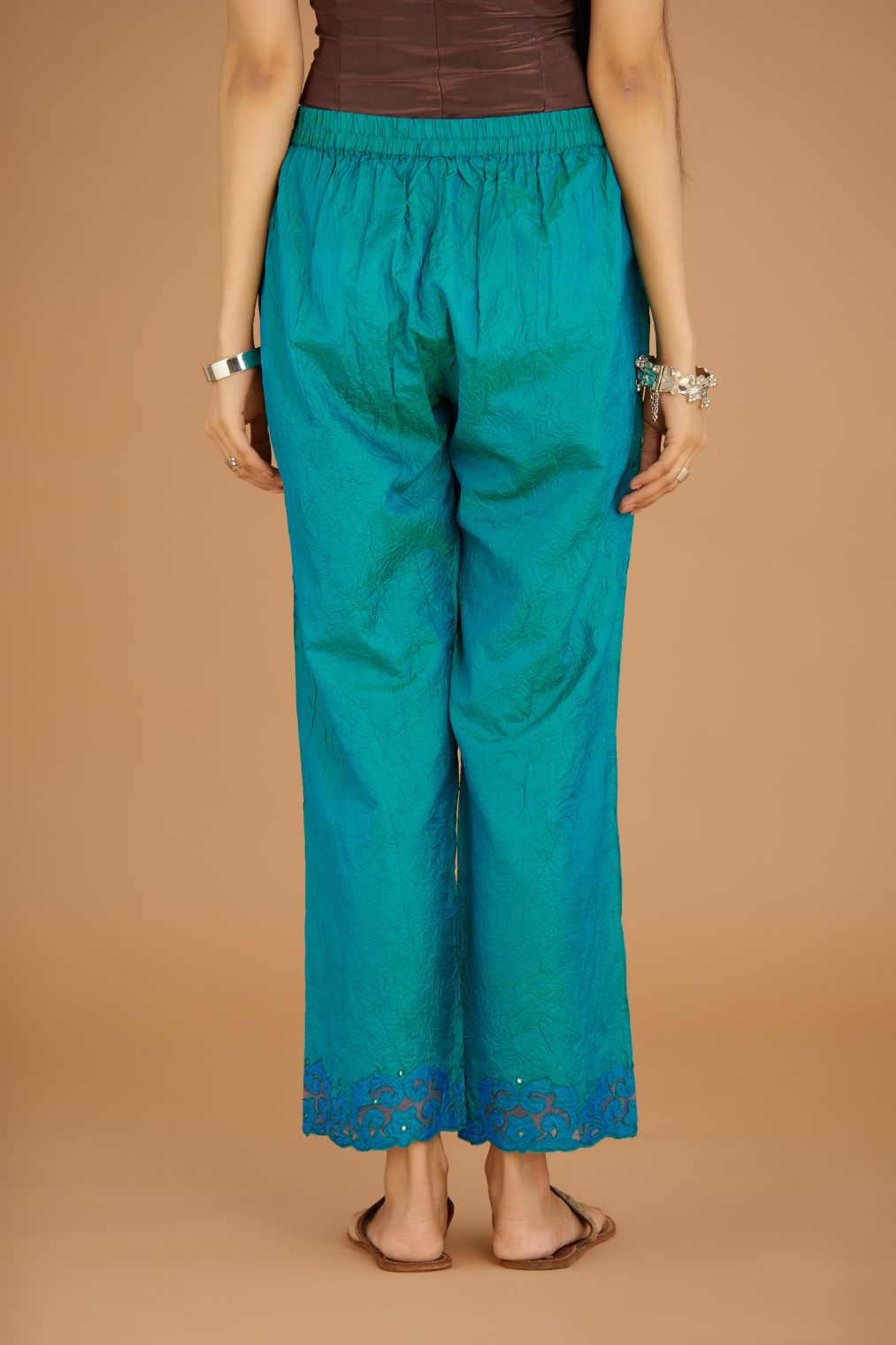 Teal blue hand crushed silk pants with contrast silk and organza fabric cutwork embroidery at bottom hem, highlighted with hand attached mirrors.