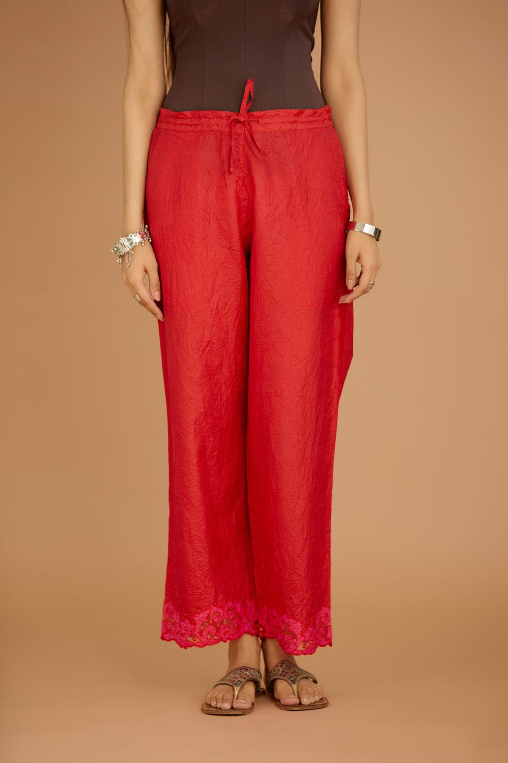 Red hand crushed silk pants with contrast silk and organza fabric cutwork embroidery at bottom hem, highlighted with hand attached mirrors.