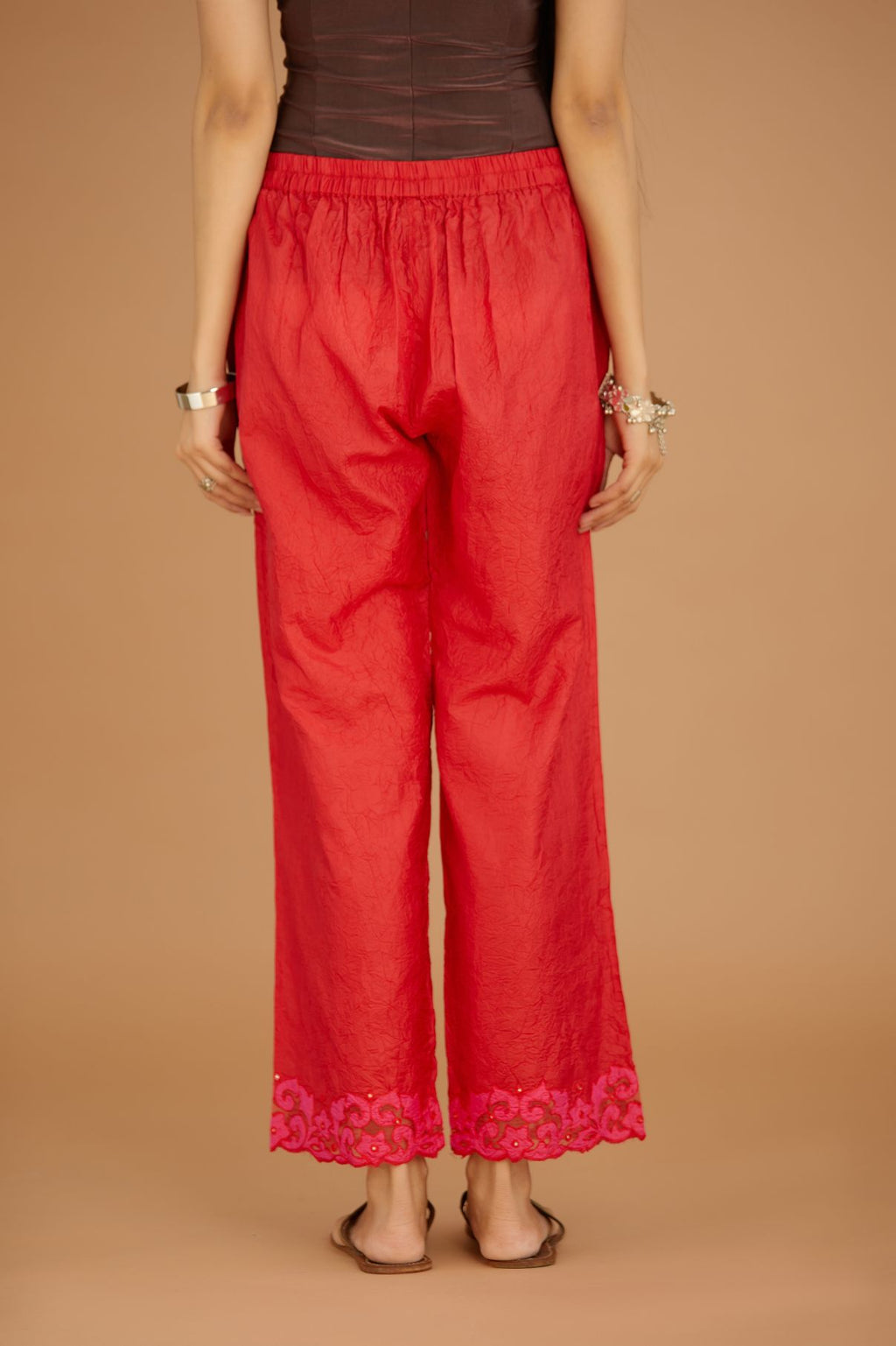 Red hand crushed silk pants with contrast silk and organza fabric cutwork embroidery at bottom hem, highlighted with hand attached mirrors.