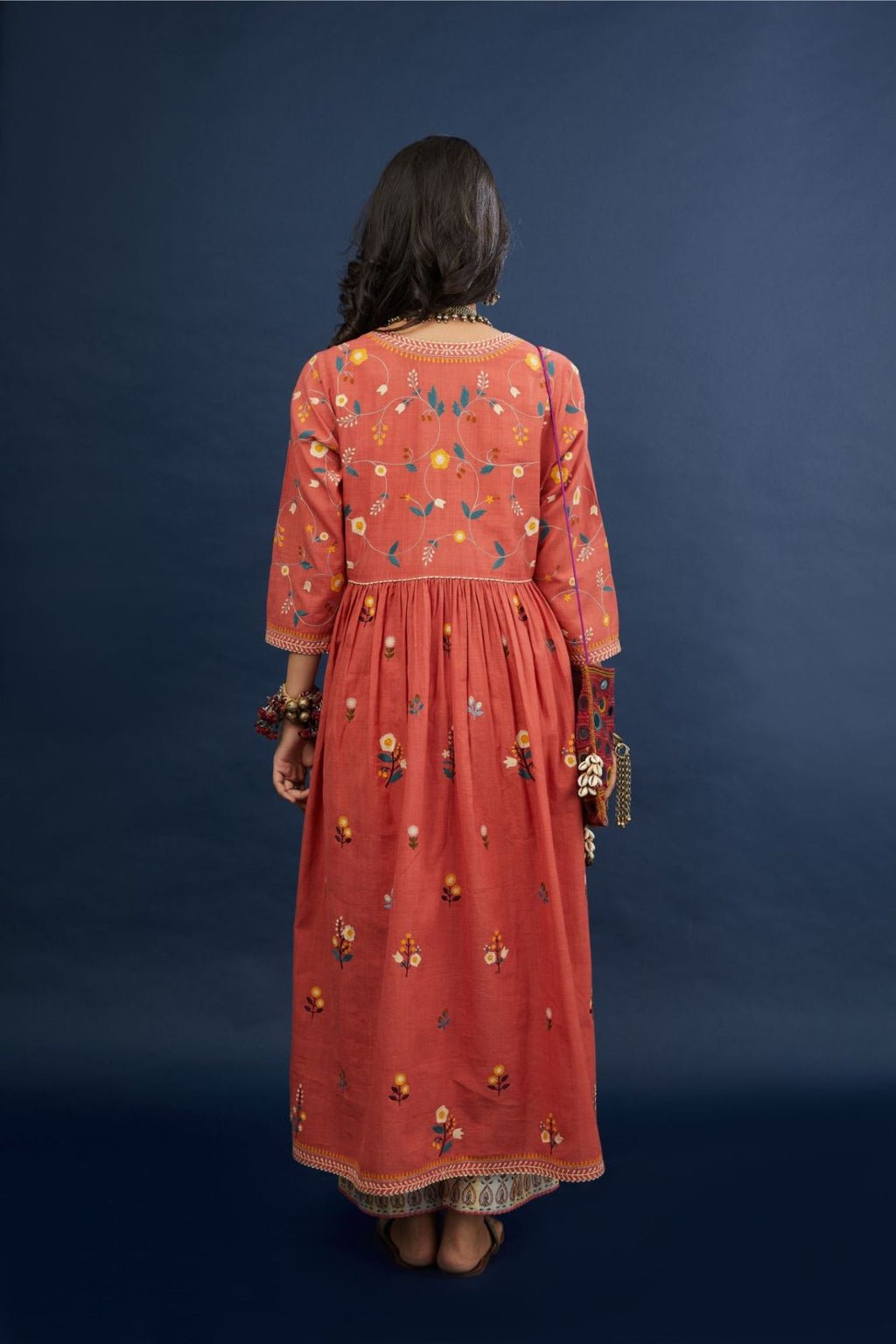 Handspun, handwoven cotton kurta set with wavy empire waistline and gathers, highlighted with all-over multi colored thread embroidery and ric-rac detail.