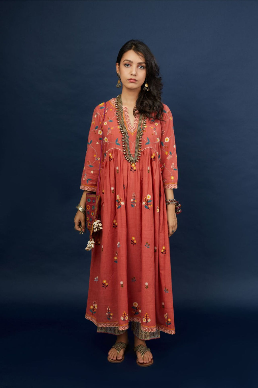 Handspun, handwoven cotton kurta set with wavy empire waistline and gathers, highlighted with all-over multi colored thread embroidery and ric-rac detail.