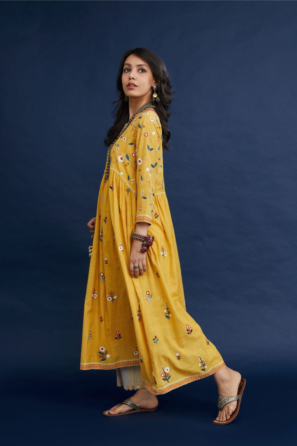 Handspun hand-woven cotton kurta with wavy empire waistline and gathers, highlighted with all-over multi colored thread embroidery, paired with hand block printed cotton pants with multi colored flower embroidery at hem
