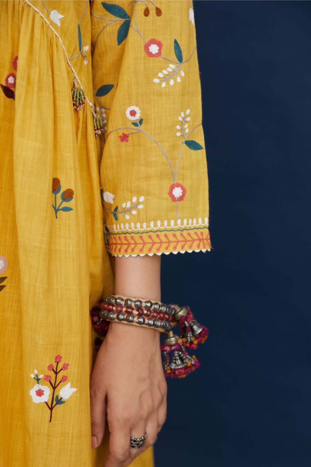 Handspun hand-woven cotton kurta with wavy empire waistline and gathers, highlighted with all-over multi colored thread embroidery, paired with hand block printed cotton pants with multi colored flower embroidery at hem