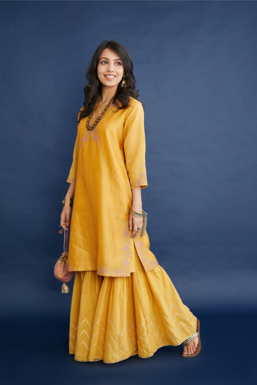 Golden yellow short kurta set highlighted with dull gold zari and contrast thread embroidery.
