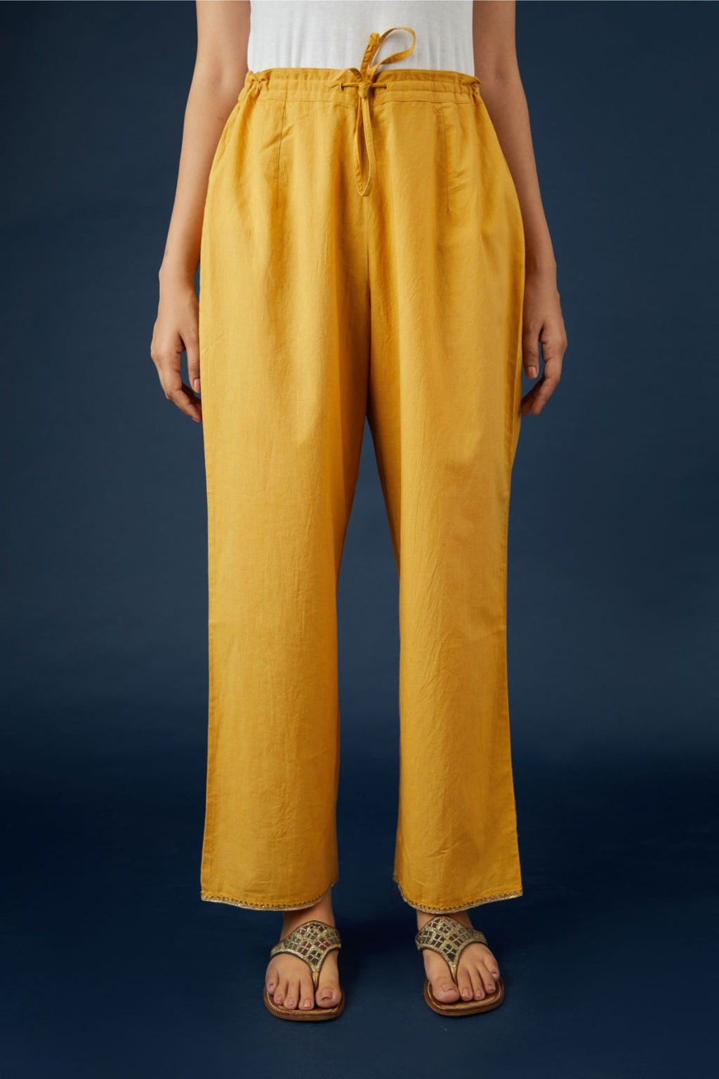 Golden yellow cotton straight pants with dull gold zari embroidery detailing at bottom hem. (Pants)