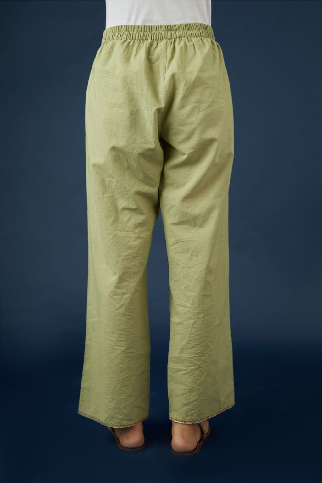 Green cotton straight pants with dull gold zari embroidery detailing at bottom hem. (Pants)