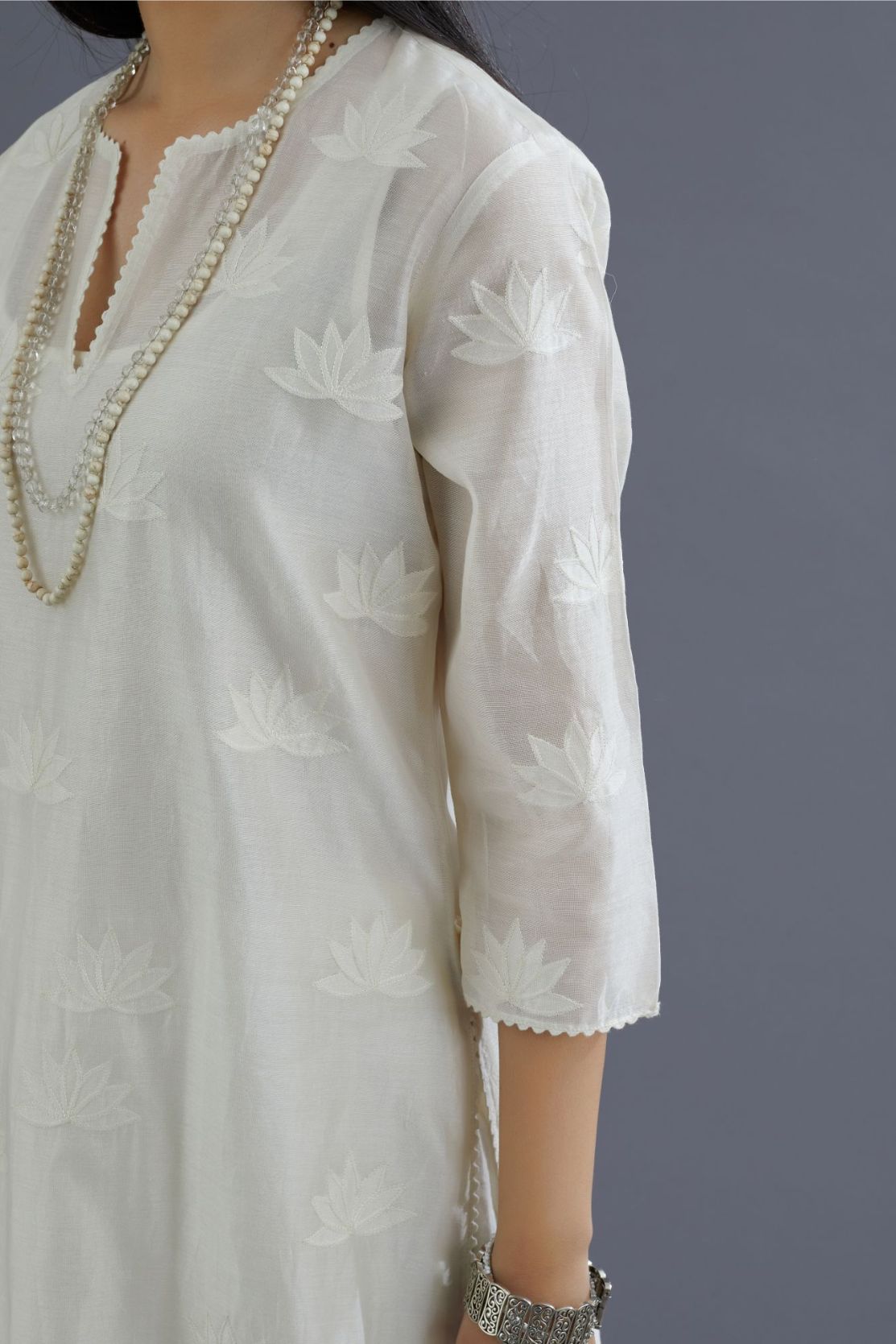 Off white silk chanderi kurta set with all-over applique lotus flower embroidery and lace detailing at neck and side slits