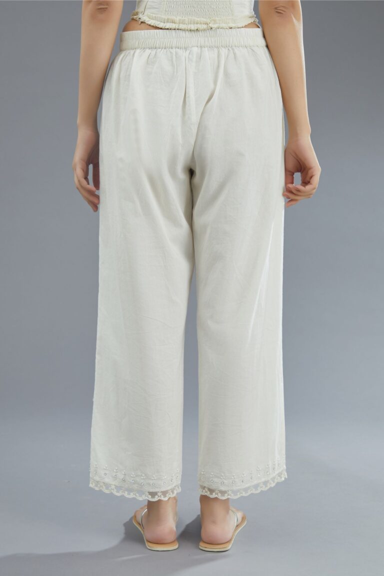 Off white straight pants detailed with lace and embroidery at bottom.