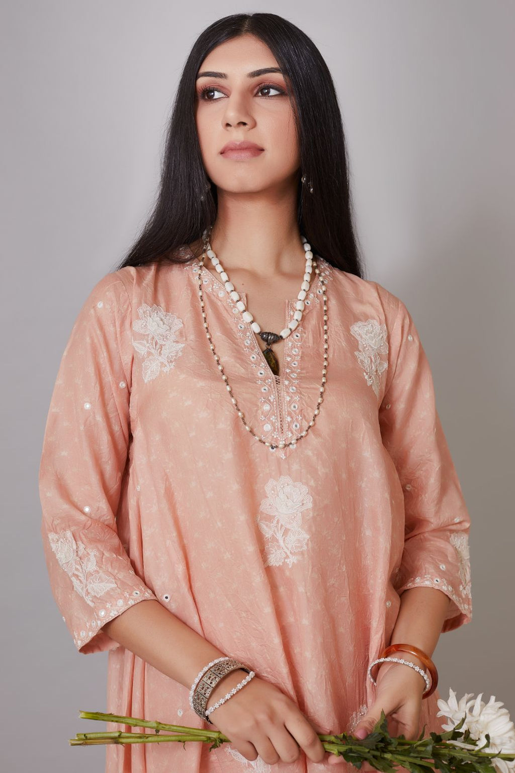 Peach hand crushed silk kurta set with asymmetric hem, mirror hand work and raised flower embroidery.