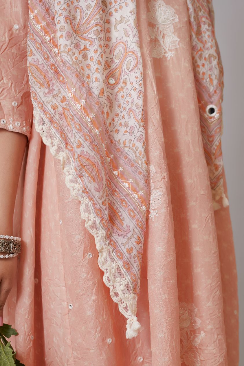 Peach hand crushed silk kurta set with asymmetric hem, mirror hand work and raised flower embroidery.