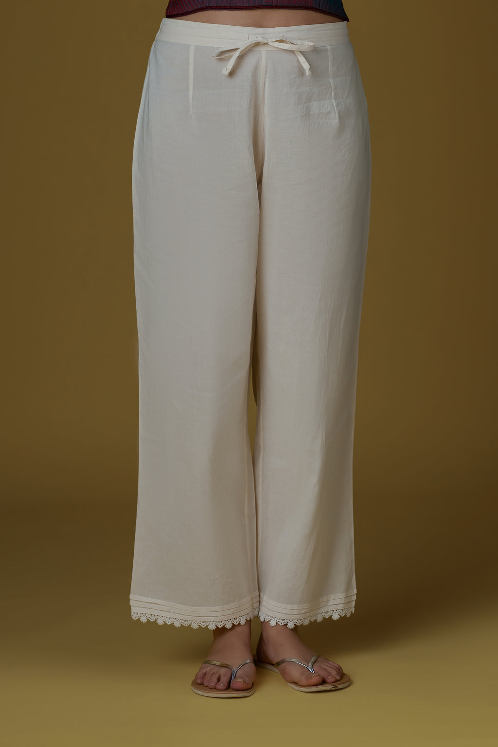 Straight pants finished with pin tucks and lace detailing at hem.