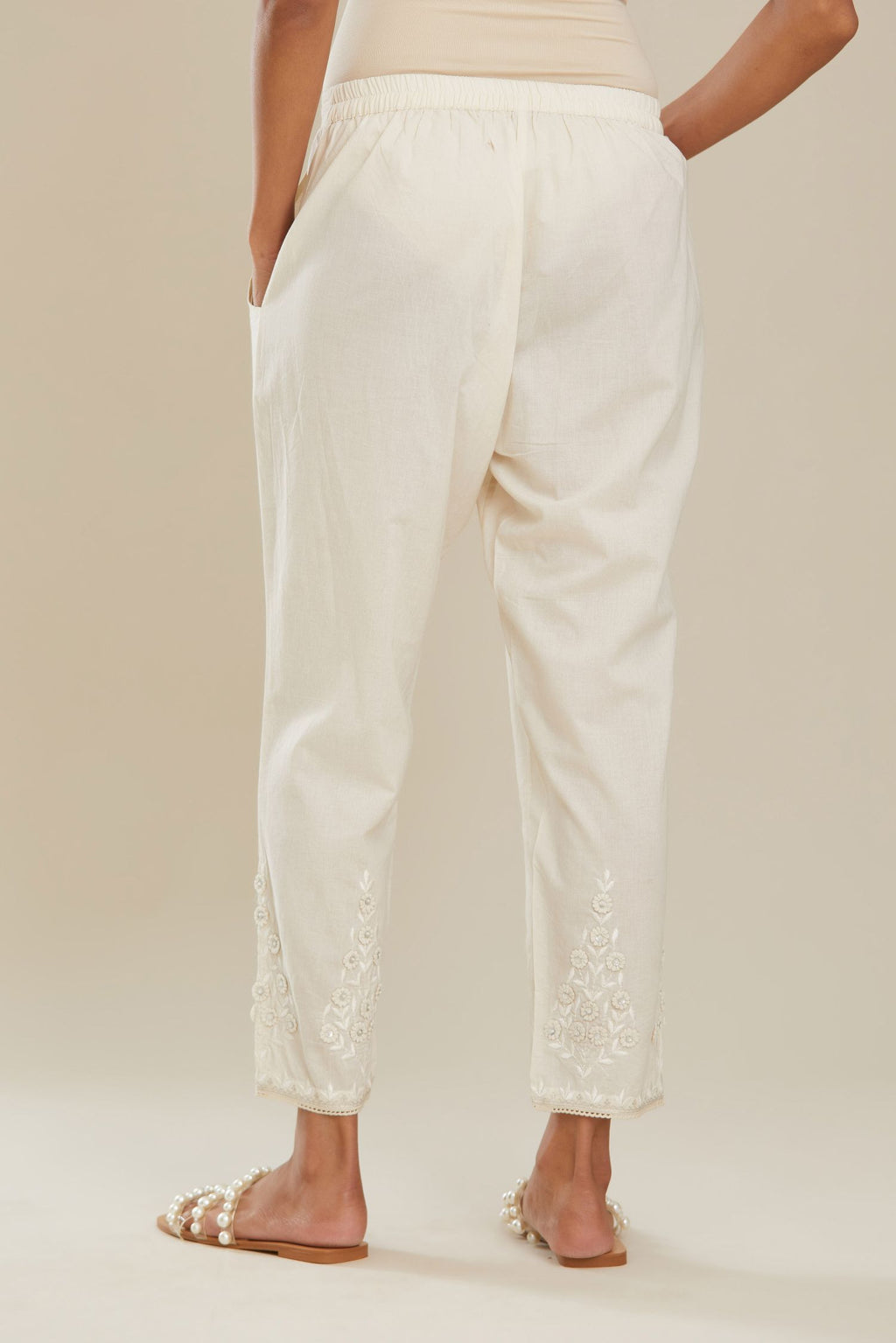 Off white cotton narrow pants with 3d embroidered flower boota at hem, highlighted with hand attached sequin and beads. Bottom hem edged with  lace. (Pants)