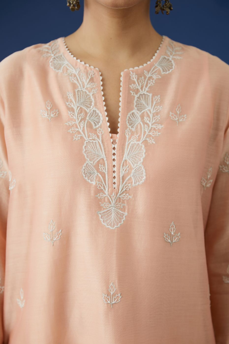 Peach silk chanderi kurta set with cutwork flower embroidery and lace detailing at neck and side slits.
