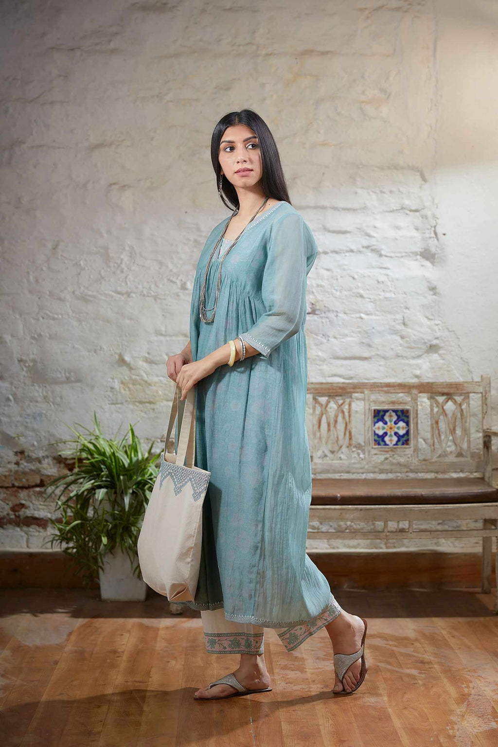 Light teal embroidered kurta with  gathered empire waist line in front and back and printed slip.
