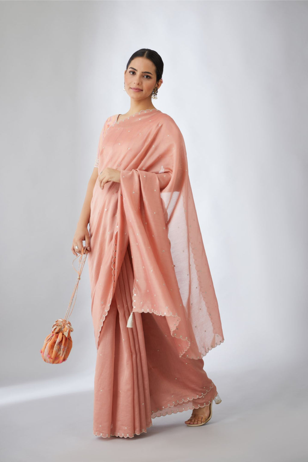 Salmon silk chanderi saree with all-over delicately embroidered silver zari flowers and scalloped edges, accentuated with hand attached mirrors (Saree+Peticot)
