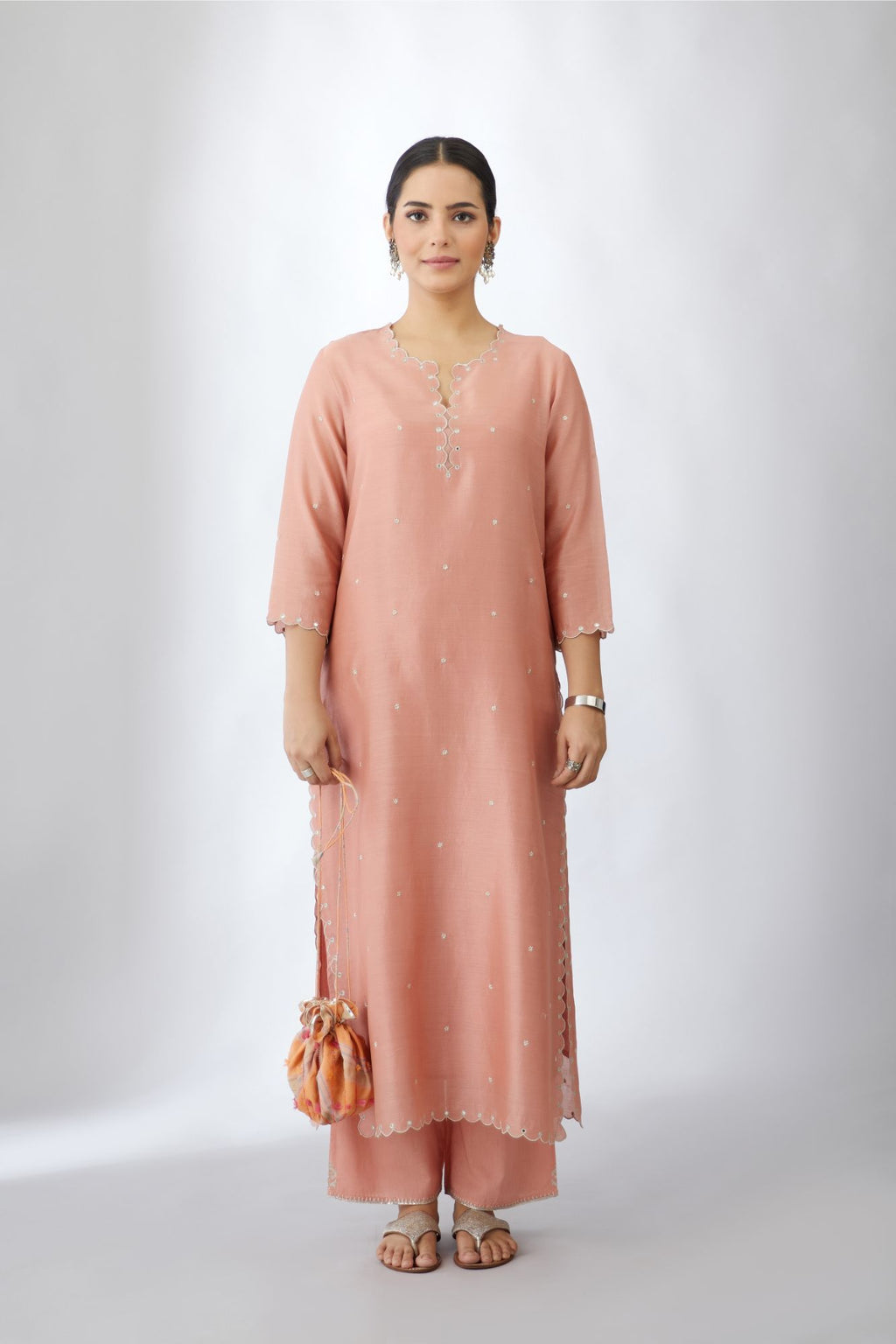 Salmon silk chanderi straight kurta set with delicate all-over silver zari flowers and scalloped edges, highlighted with hand attached mirrors.