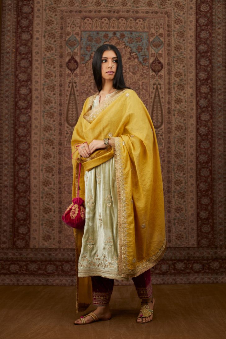 Soft green silk velvet kurta set with gold gota and zari embroidery butas and heavy borders at hem.