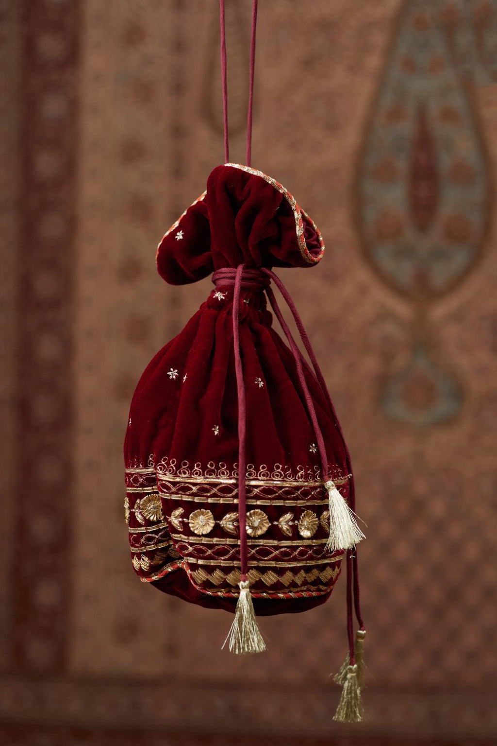 Silk Velvet potli with drawstrings and a shoulder string. It has gold gota and zari embroidery at the bottom and small butis all over (Potli)