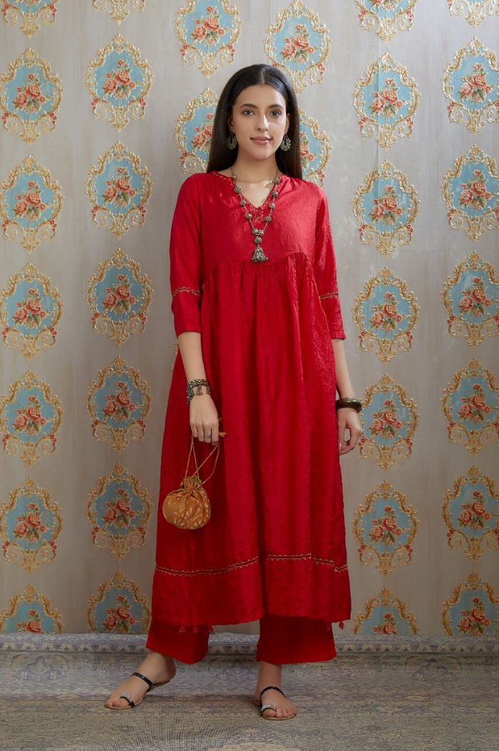 Red hand-crushed silk kurta with wavy empire waistline and gathers, highlighted with beaded tassels and pulled thread embroidery, paired with hand crushed silk pants.