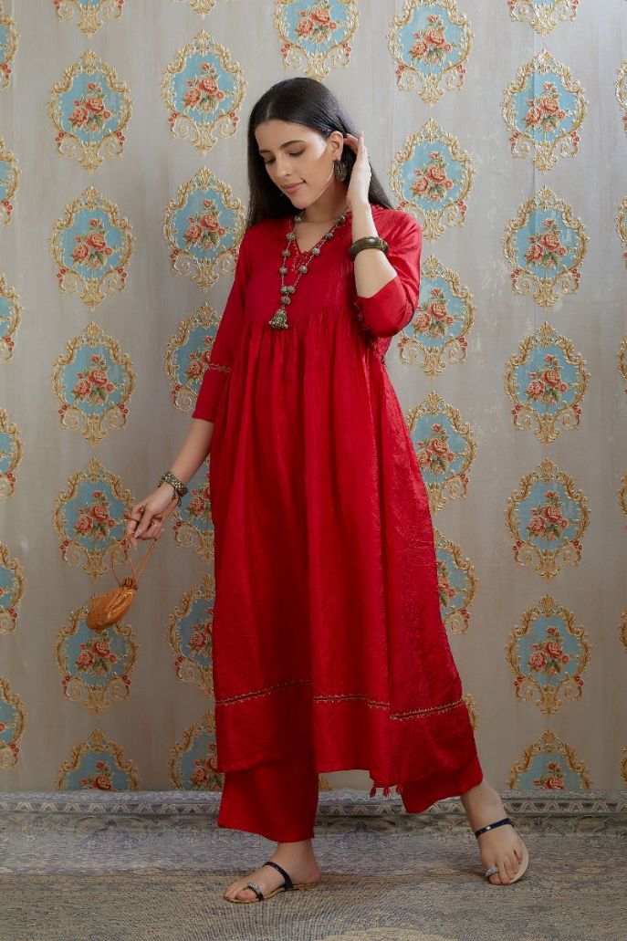 Red hand-crushed silk kurta with wavy empire waistline and gathers, highlighted with beaded tassels and pulled thread embroidery, paired with hand crushed silk pants.