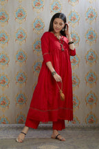 Red hand-crushed silk kurta with wavy empire waistline and gathers, highlighted with beaded tassels and pulled thread embroidery, paired with hand crushed silk pants.