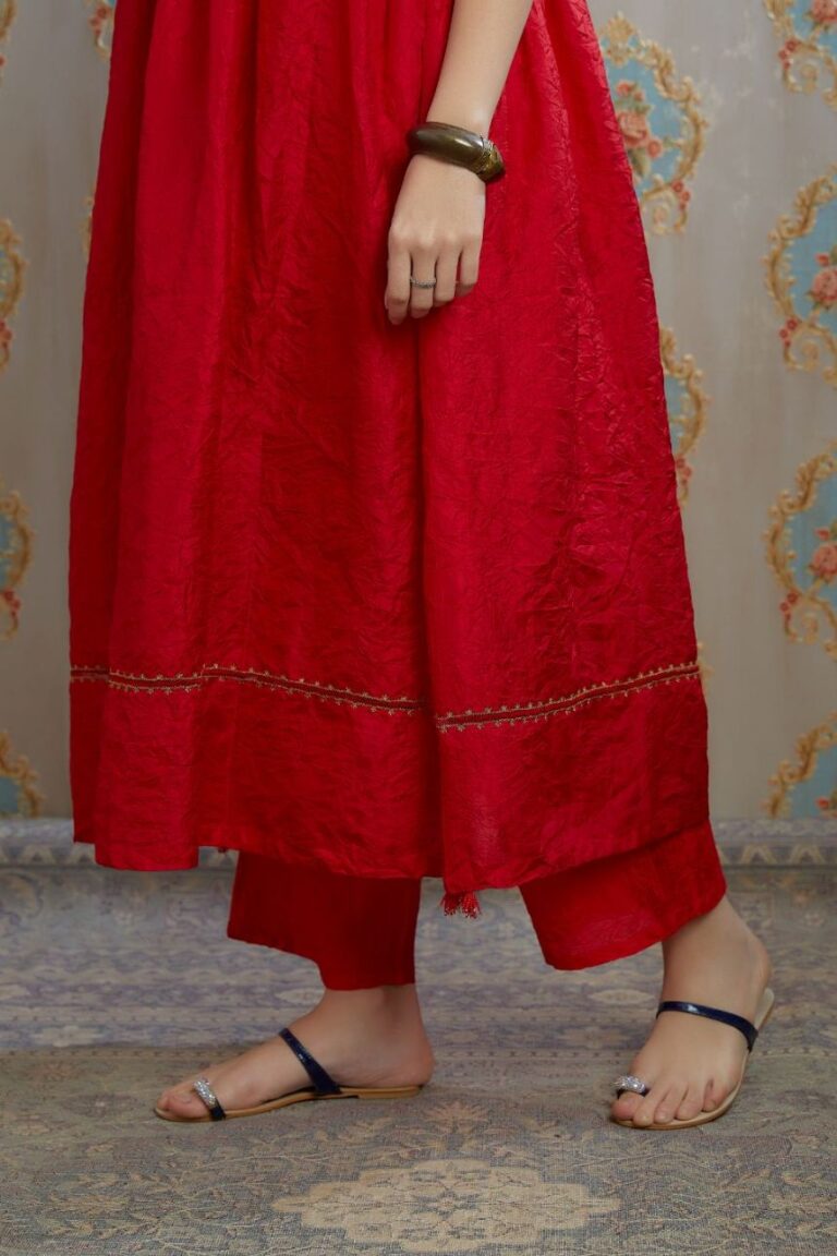 Red hand-crushed silk kurta with wavy empire waistline and gathers, highlighted with beaded tassels and pulled thread embroidery, paired with hand crushed silk pants.