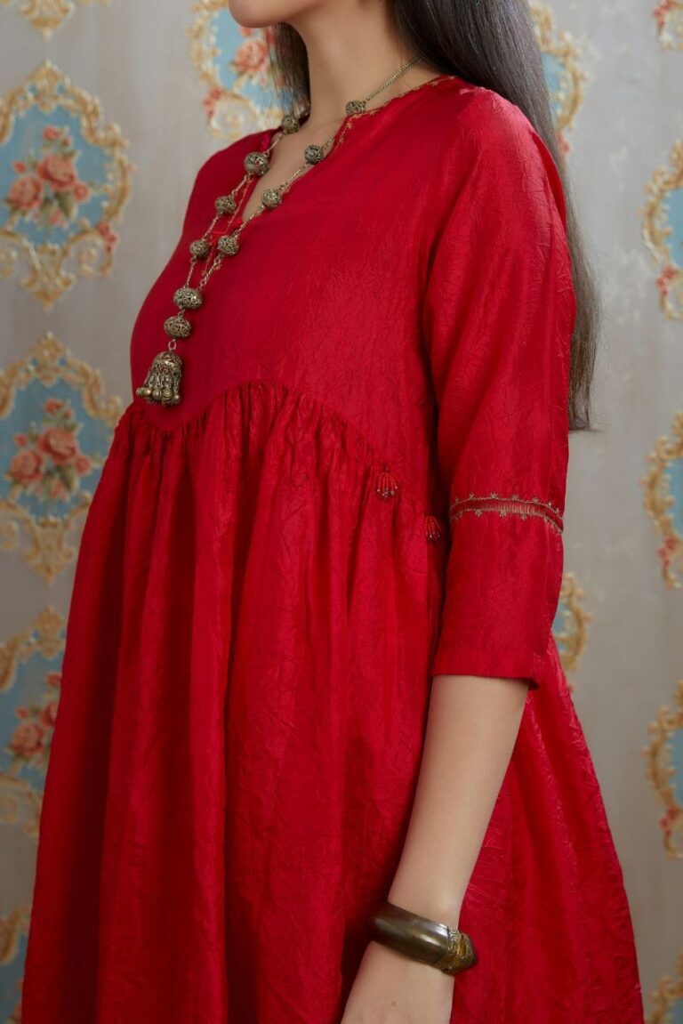 Red hand-crushed silk kurta with wavy empire waistline and gathers, highlighted with beaded tassels and pulled thread embroidery, paired with hand crushed silk pants.