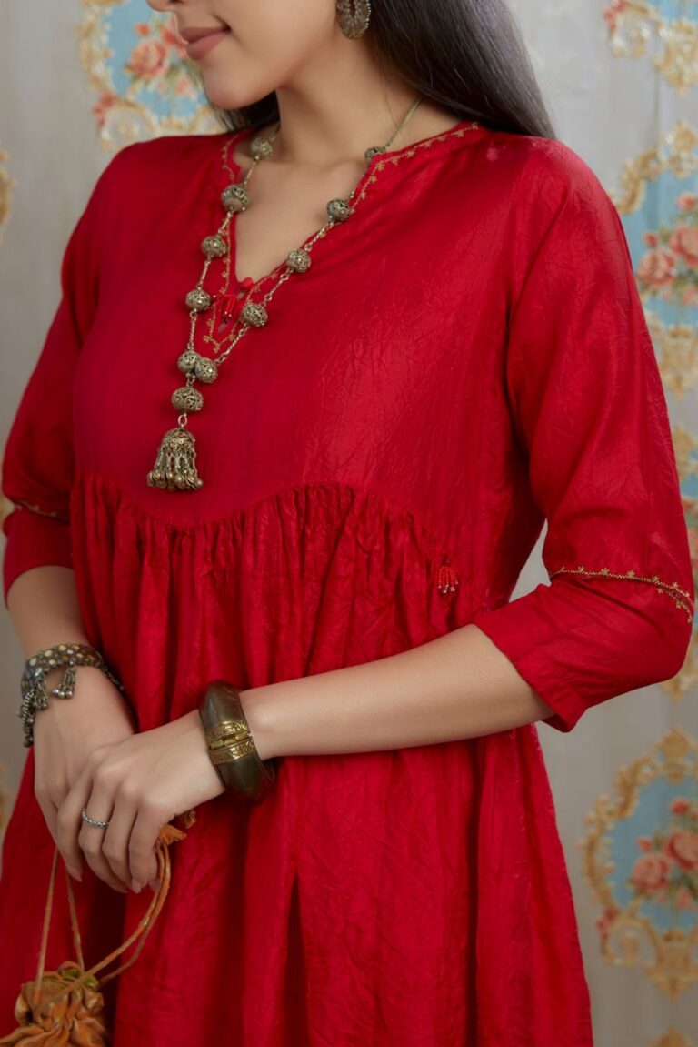 Red hand-crushed silk kurta with wavy empire waistline and gathers, highlighted with beaded tassels and pulled thread embroidery, paired with hand crushed silk pants.