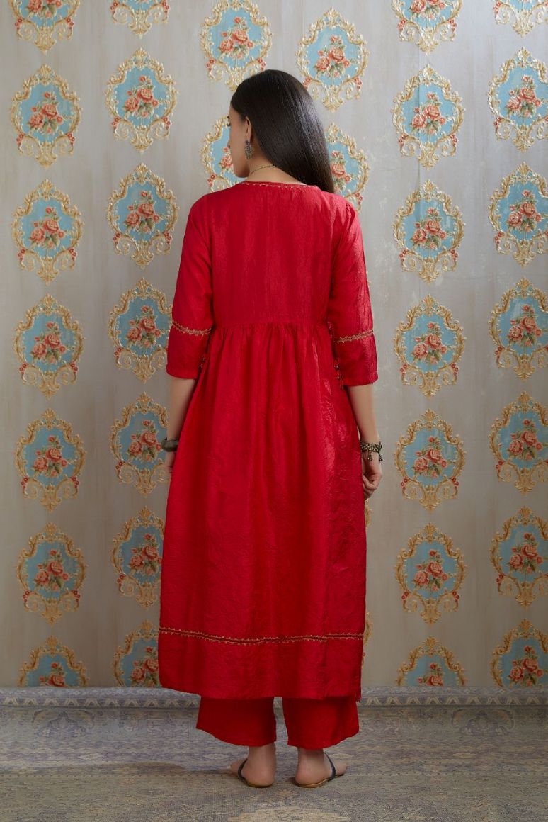 Red hand-crushed silk kurta with wavy empire waistline and gathers, highlighted with beaded tassels and pulled thread embroidery, paired with hand crushed silk pants.