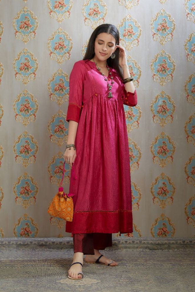 Fuchsia hand-crushed silk kurta set with wavy empire waistline and gathers, highlighted with beaded tassels and pulled thread embroidery.