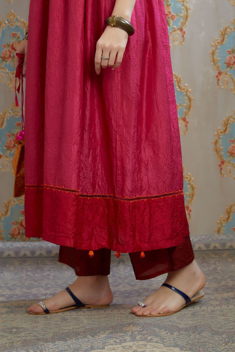 Fuchsia hand-crushed silk kurta set with wavy empire waistline and gathers, highlighted with beaded tassels and pulled thread embroidery.