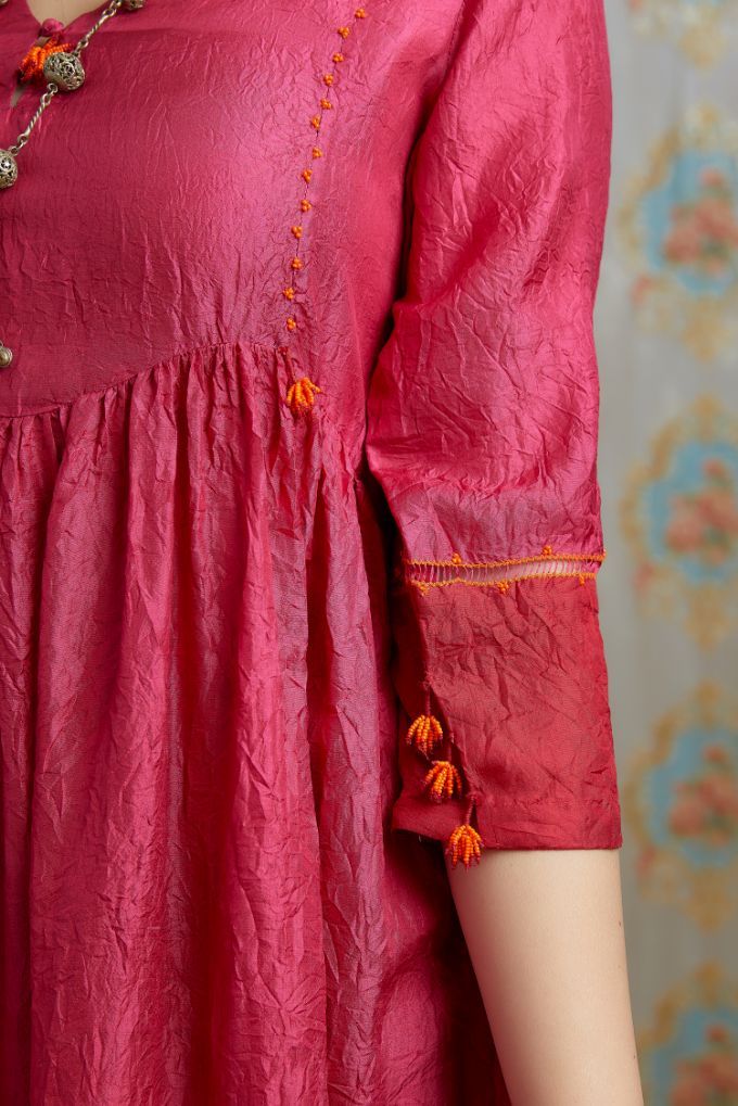Fuchsia hand-crushed silk kurta set with wavy empire waistline and gathers, highlighted with beaded tassels and pulled thread embroidery.