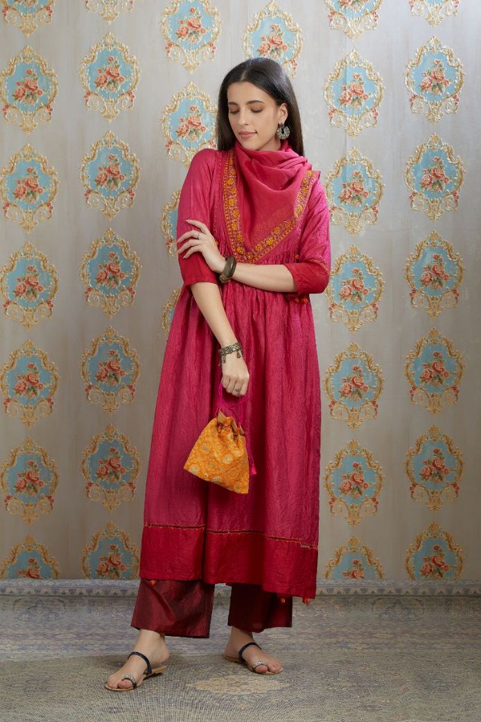 Fuchsia hand-crushed silk kurta set with wavy empire waistline and gathers, highlighted with beaded tassels and pulled thread embroidery.