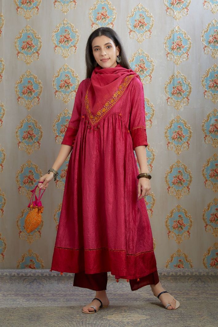 Fuchsia hand-crushed silk kurta set with wavy empire waistline and gathers, highlighted with beaded tassels and pulled thread embroidery.