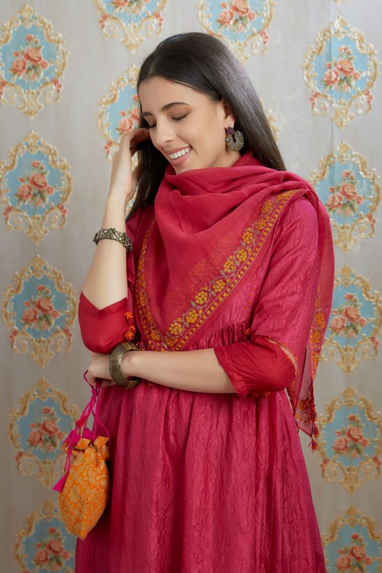 Fuchsia hand-crushed silk kurta set with wavy empire waistline and gathers, highlighted with beaded tassels and pulled thread embroidery.