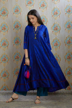 Asymmetric hem blue hand crushed silk kurta with pulled thread embroidery, paired with hand crushed silk pants.